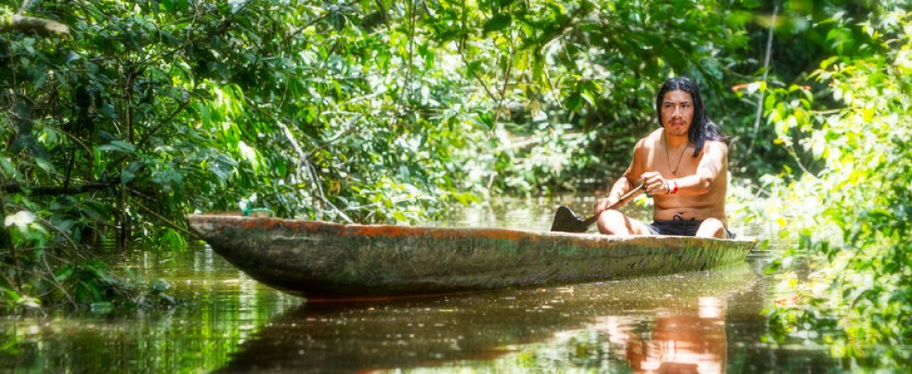 A native American paddling his pirogue along an Amazon estuary. 