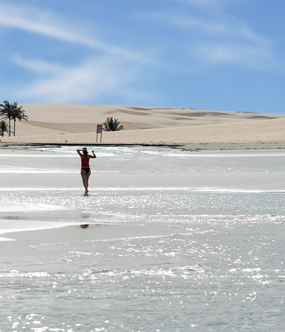 A woman enjoys walking accross a shimmering lagoon in Jericoacoara. 