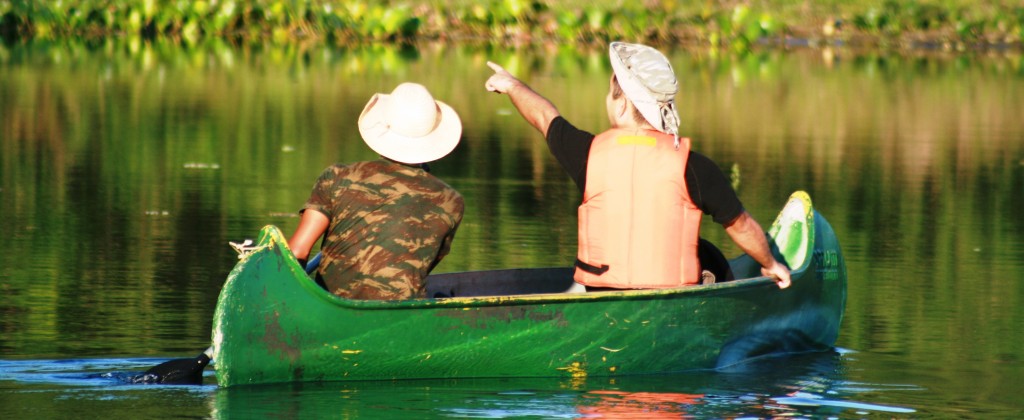 An excited bird watcher points from his canoe in Pantanal.