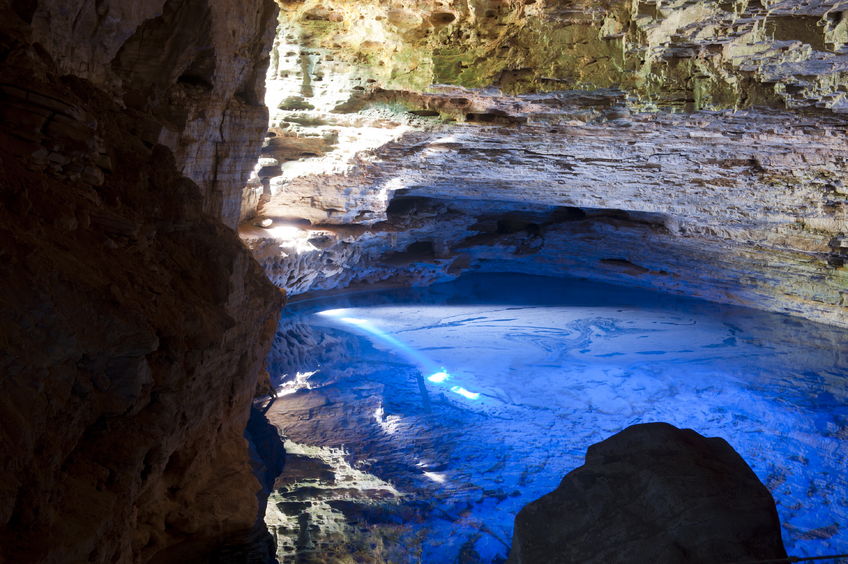 The sun bouncing off the water lights a cave up in a glowing blue colour. 