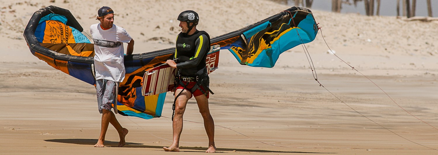 Kitesurfer and instructor walk along the beach in Brazil.