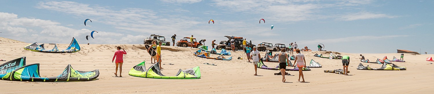 A panoramic view of people on the beach getting ready to kitesurf.