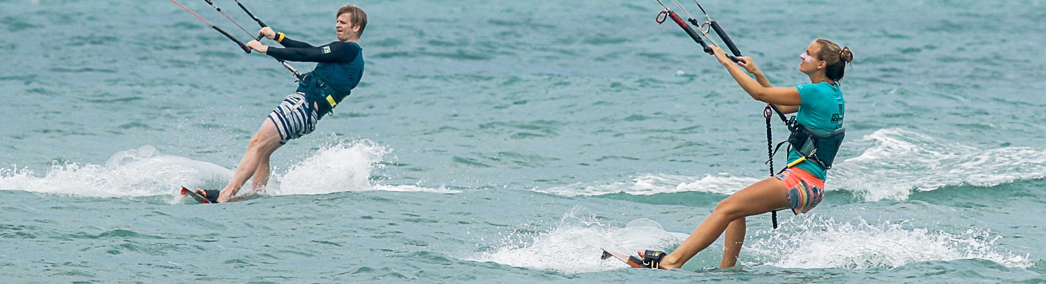 Panoramic shot of a man and woman kitesurfer riding in the ocean.