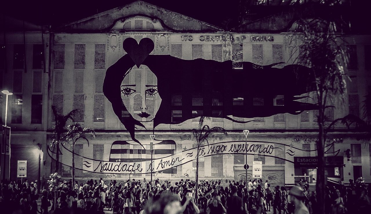 Black and white photo of crowd watching a projection on a wall in Brazil.