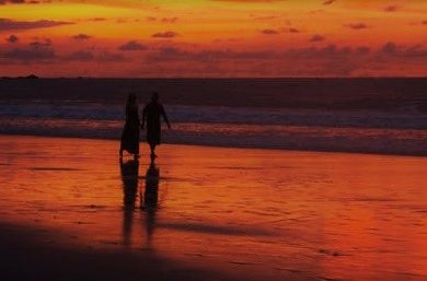 Couple walk on the beach at sunset on their Brazilian Honeymoon Package Tour.